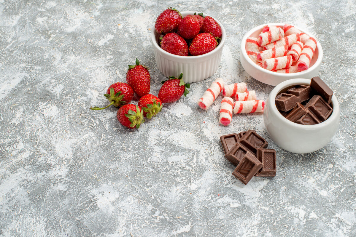 巧克力底部视图碗与草莓巧克力糖果和一些草莓巧克力糖果在灰白色马赛克背景的右侧糖果食品水果