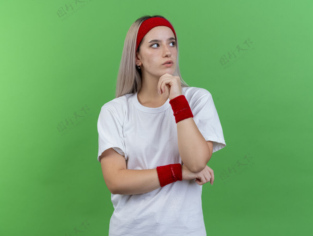 手自信的年轻白人运动女孩戴着背带和头带头带壁板下巴