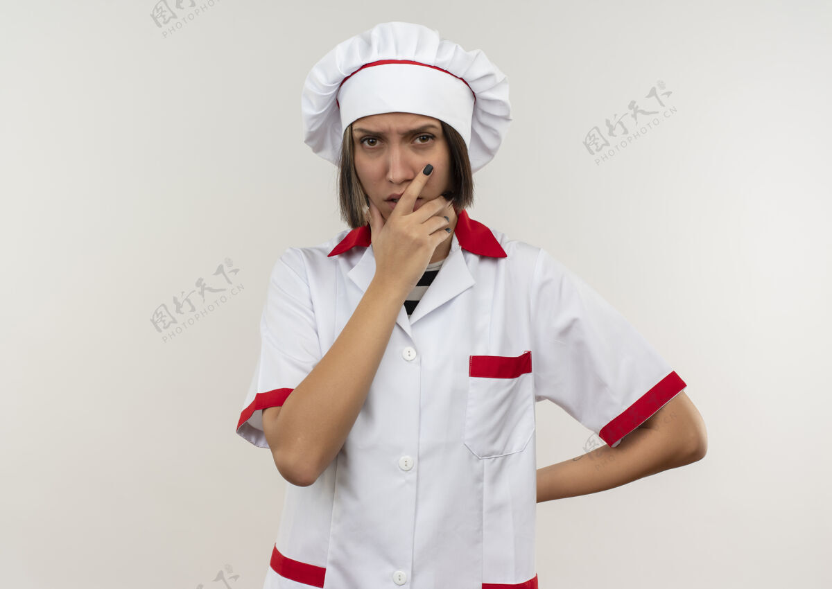 衣服体贴的年轻女厨师 穿着厨师制服 手放在下巴上 另一只手放在后面 隔离在白墙上另一个人表情