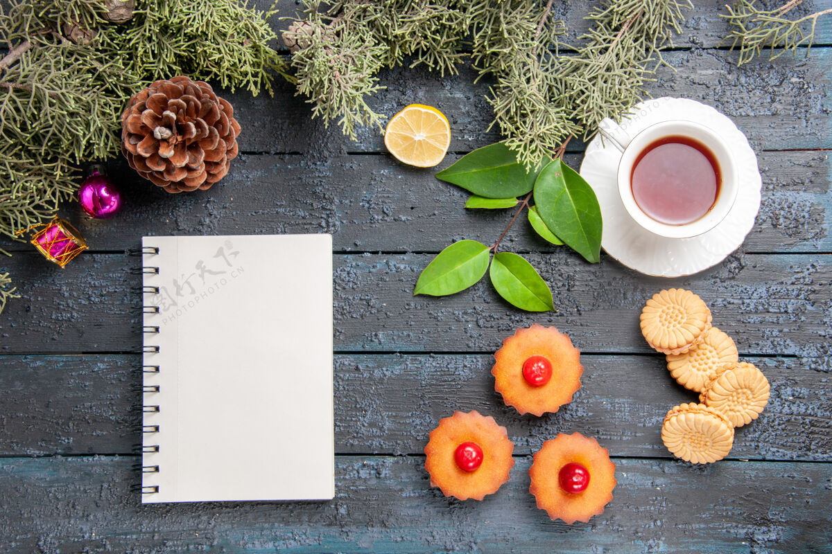 棕色顶视图樱桃纸杯蛋糕杉树树枝柠檬片一杯茶饼干和一个笔记本在深色的木桌上食物杯子木头