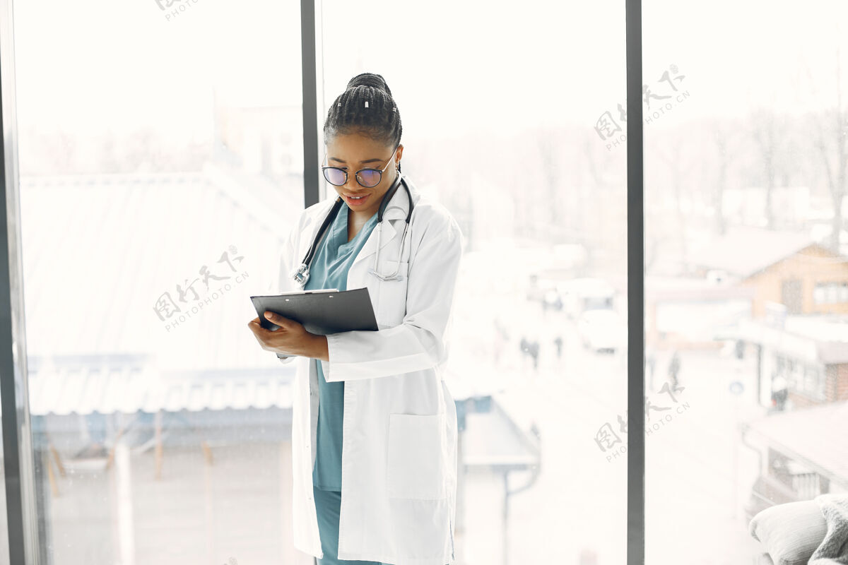 美丽长着可怕的长发的女人皮肤黝黑的医生穿着医院长袍的女人室内建议工作