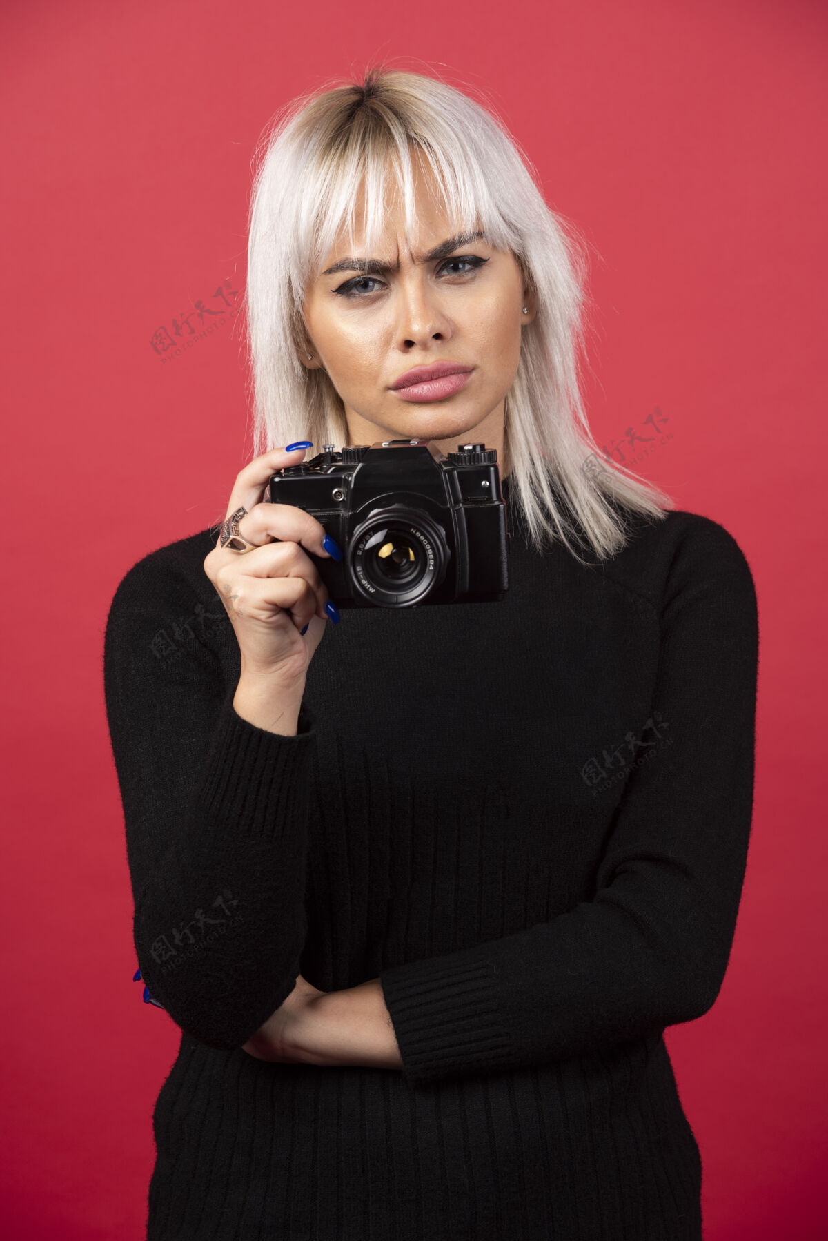 人类美丽的年轻女子手持相机站在红色背景下高品质的照片女性摄影师年轻人