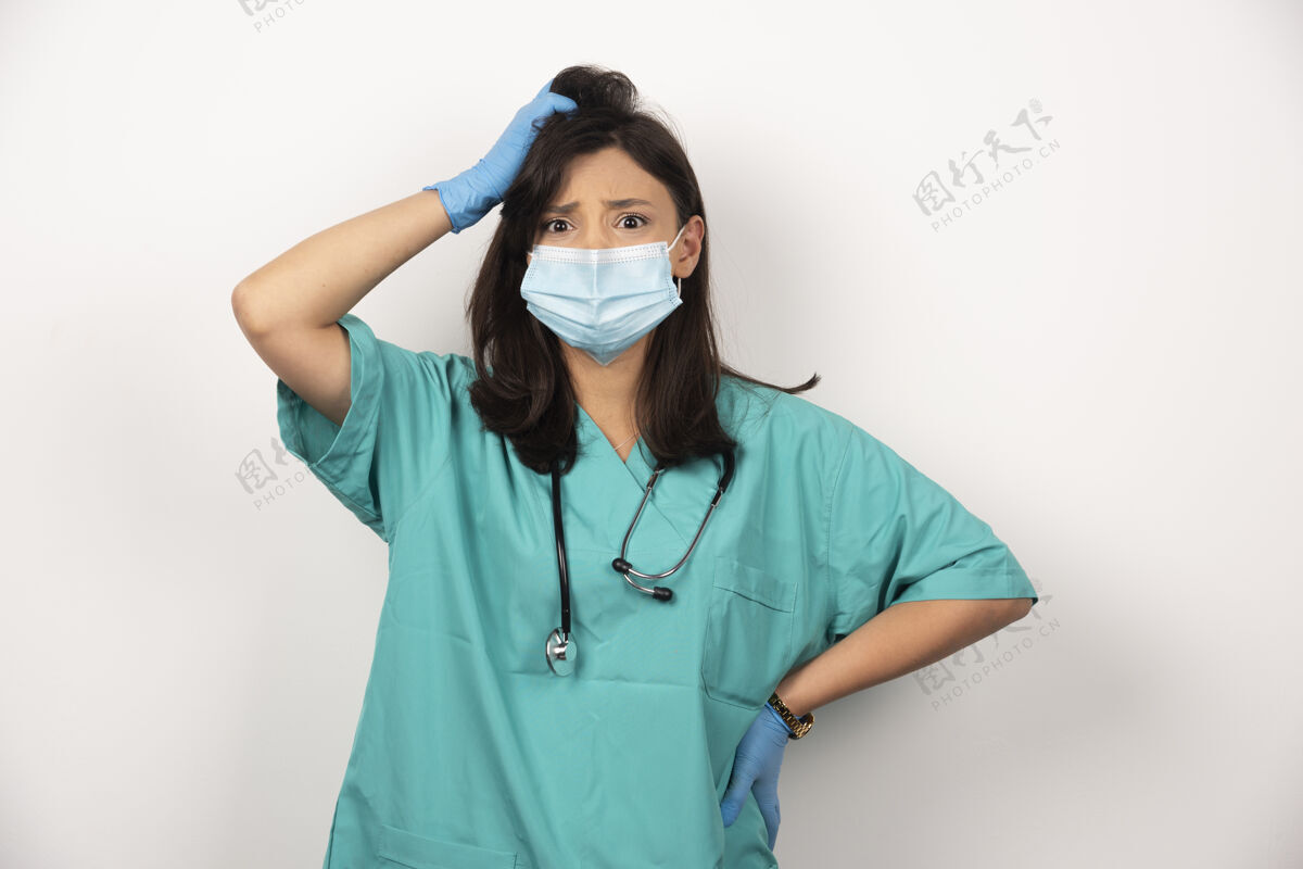 手套困惑的医生戴着医用面罩和手套思考着白色的背景高质量的照片面罩听诊器女性