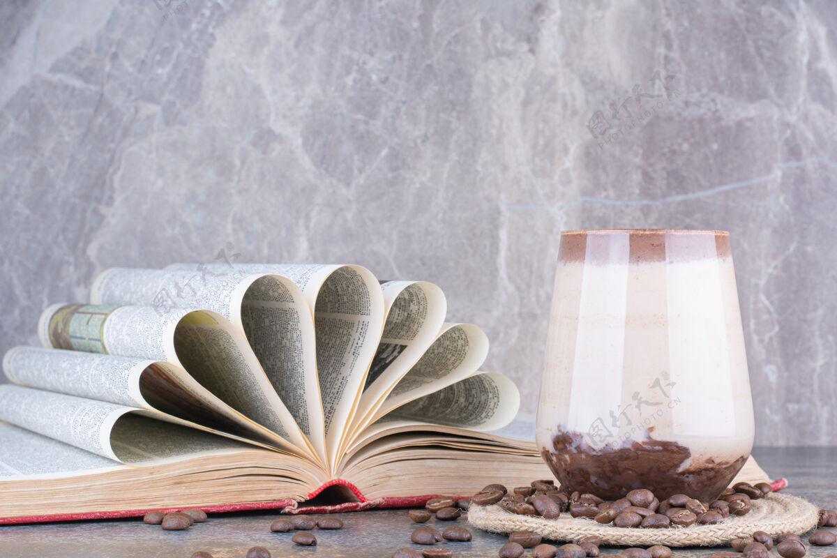 芳香一杯牛奶 一本打开的书和大理石上的咖啡豆热的可口大理石