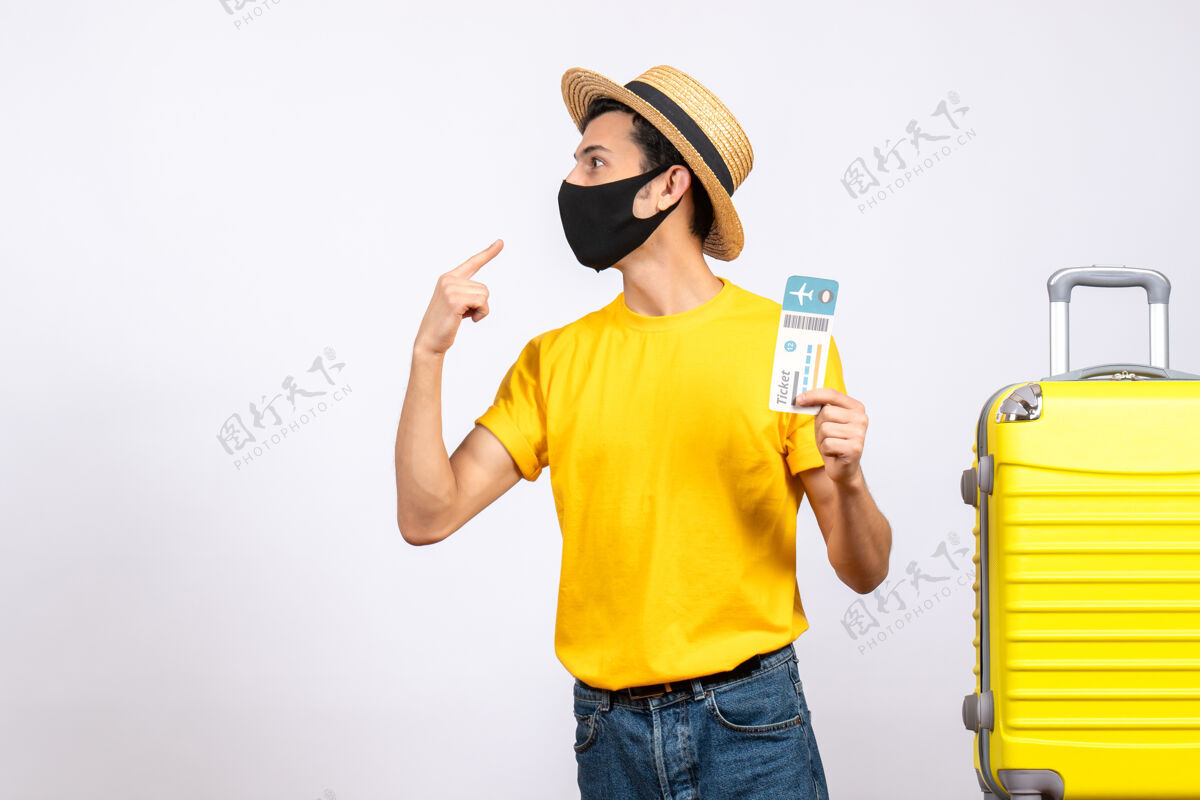 稻草正面图：戴草帽 穿着黄色t恤的年轻人站在黄色手提箱旁 手里拿着机票男性T恤年轻人