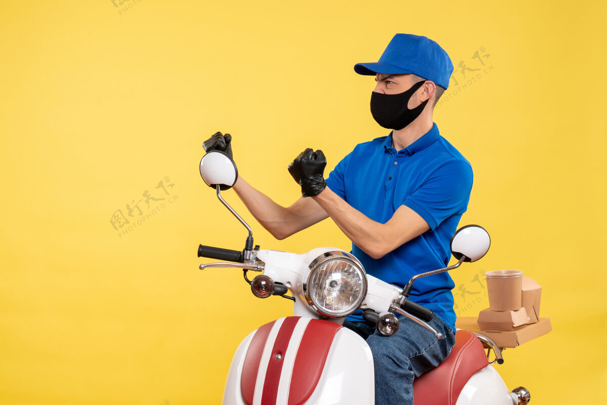 年轻男性信使正面图黄色背景上身穿蓝色制服的年轻男性快递员柯维德-大流行快递服务工作病毒自行车工作病毒男性工作