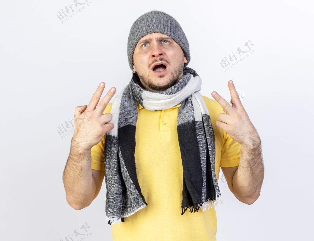 人年轻的金发病患戴着冬天的帽子和围巾 双手孤立在白墙上 打着胜利手势手势斯拉夫人围巾