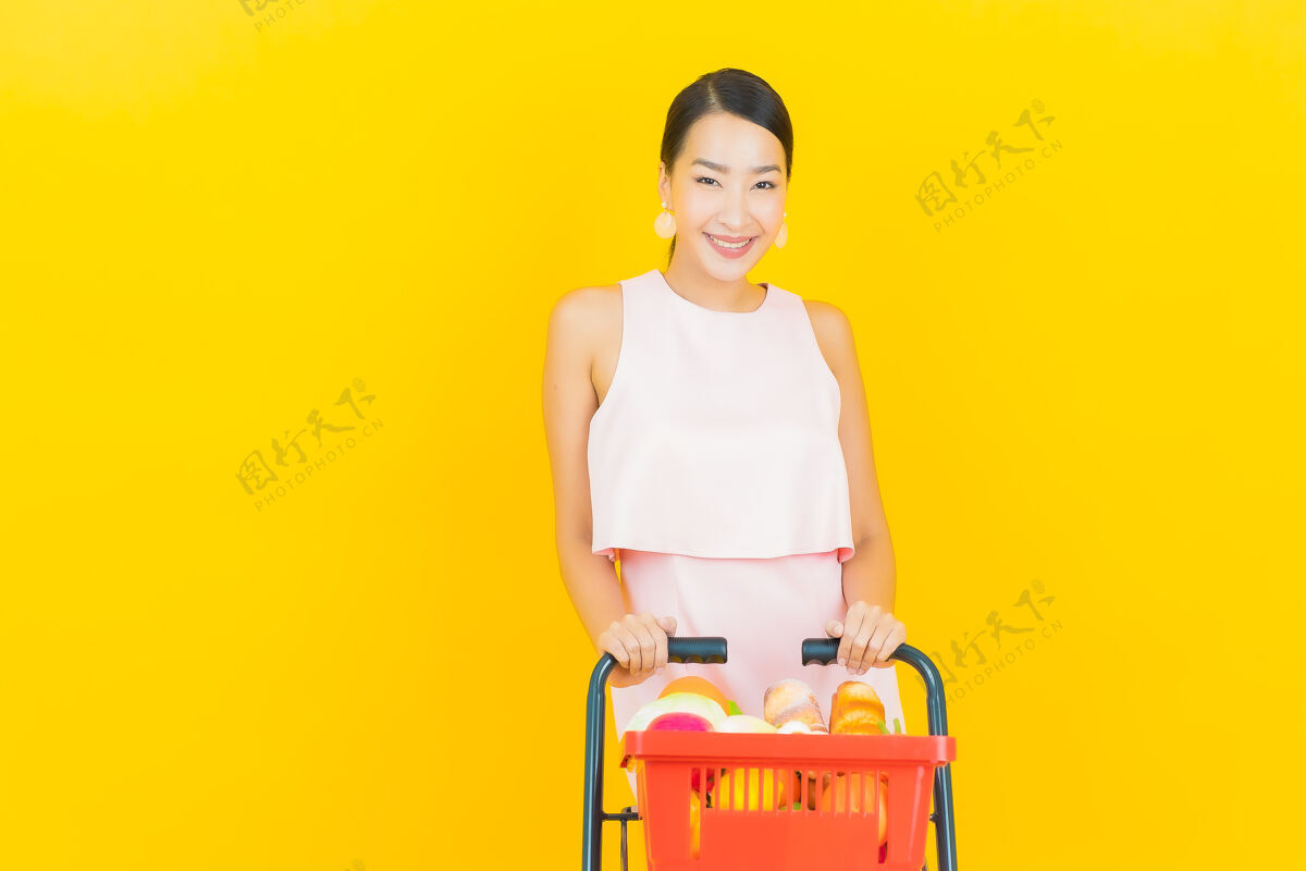 篮子肖像美丽的亚洲年轻女子微笑着从黄色超市购物篮营养女性成人