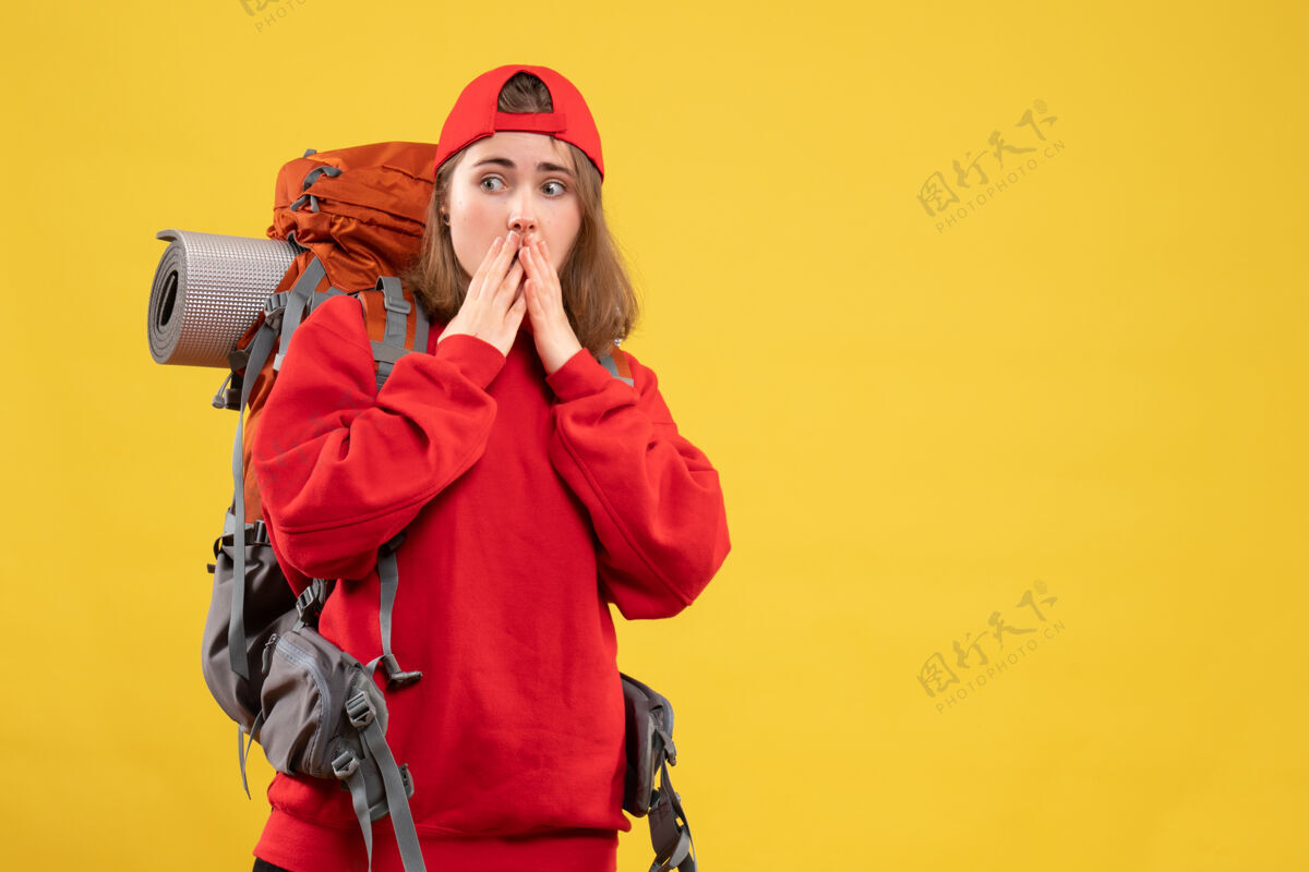 抱正面图：年轻游客背着背包 戴着红帽子 手放在嘴上前面成人嘴
