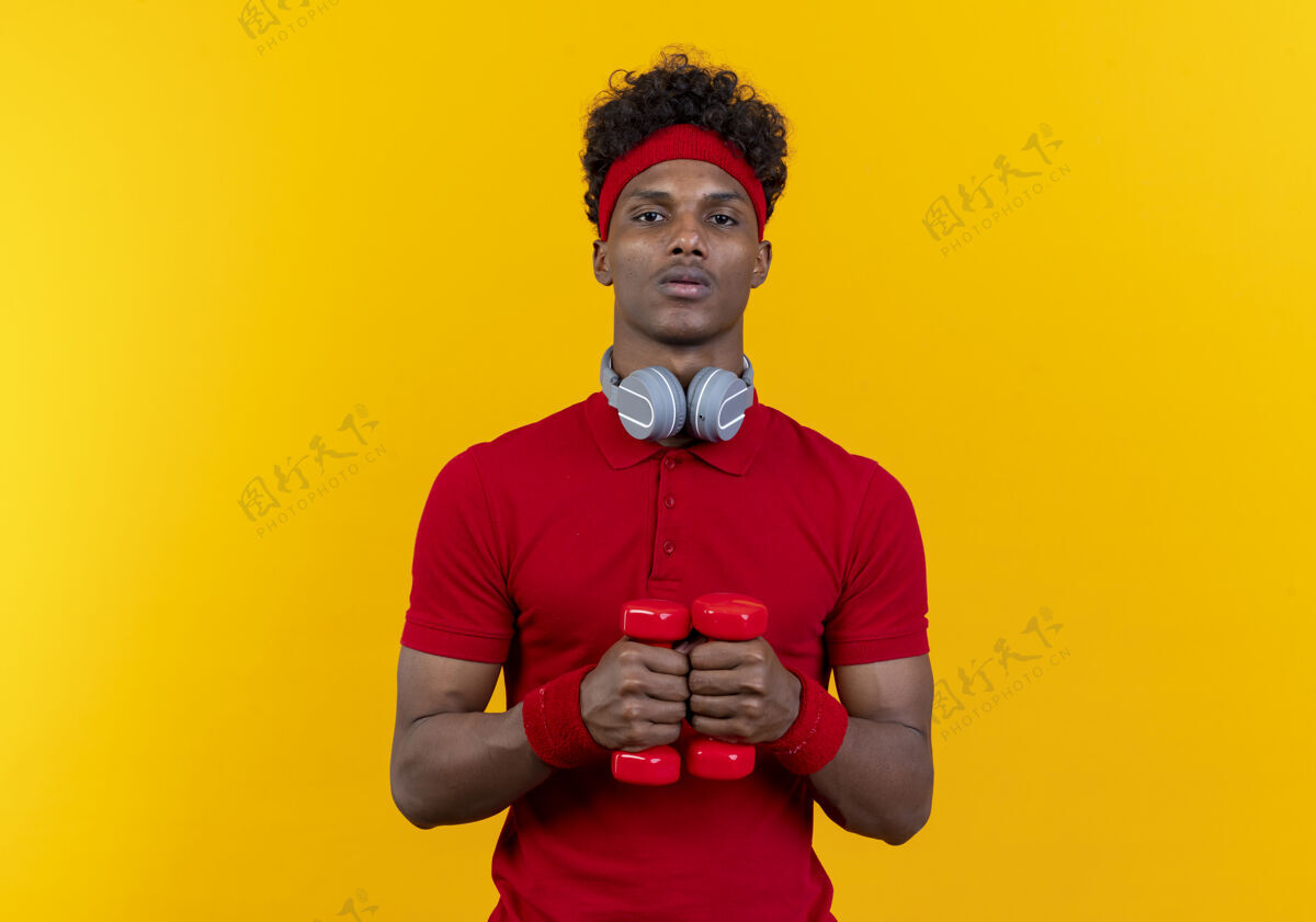 年轻看着镜头年轻的美国黑人运动男子戴着头带和手环举着哑铃男人哑铃黄色