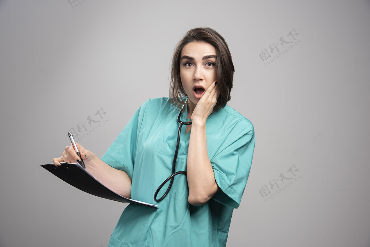 听诊器身着蓝色制服的医生站在灰色的背景上高质量的照片肖像健康工作