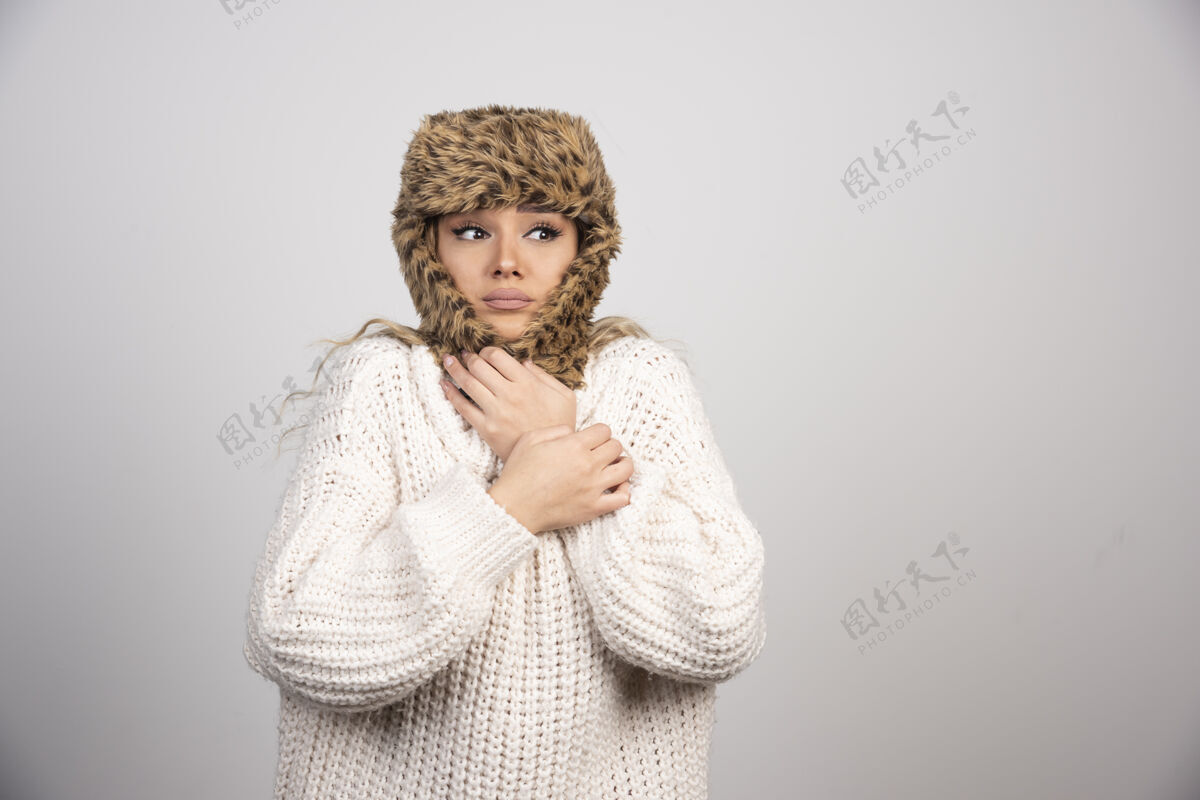 帽子穿白色针织毛衣的年轻女子感觉很冷女士女士针织