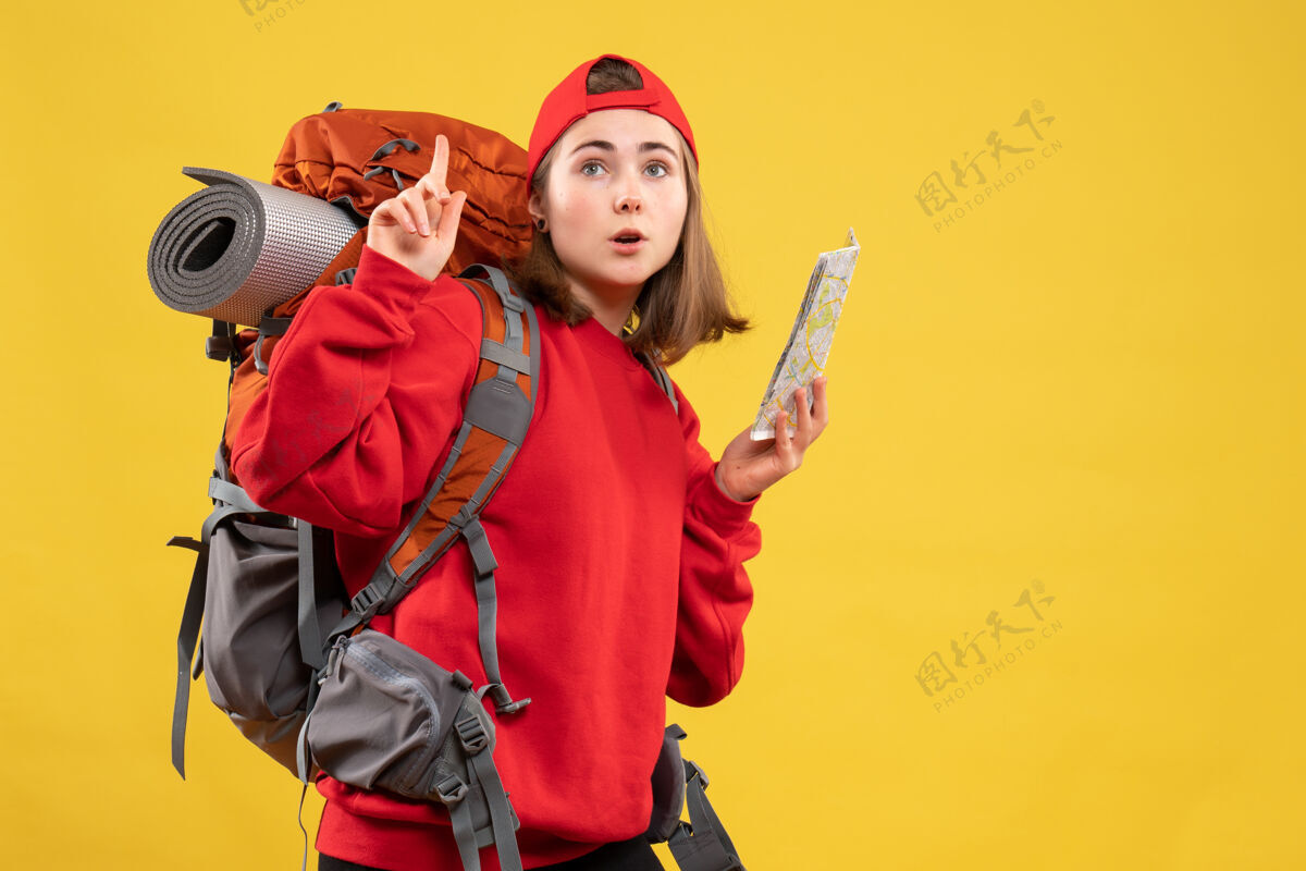 武器正面图漂亮的女旅行者背着背包拿着地图指着天花板成人指向背包