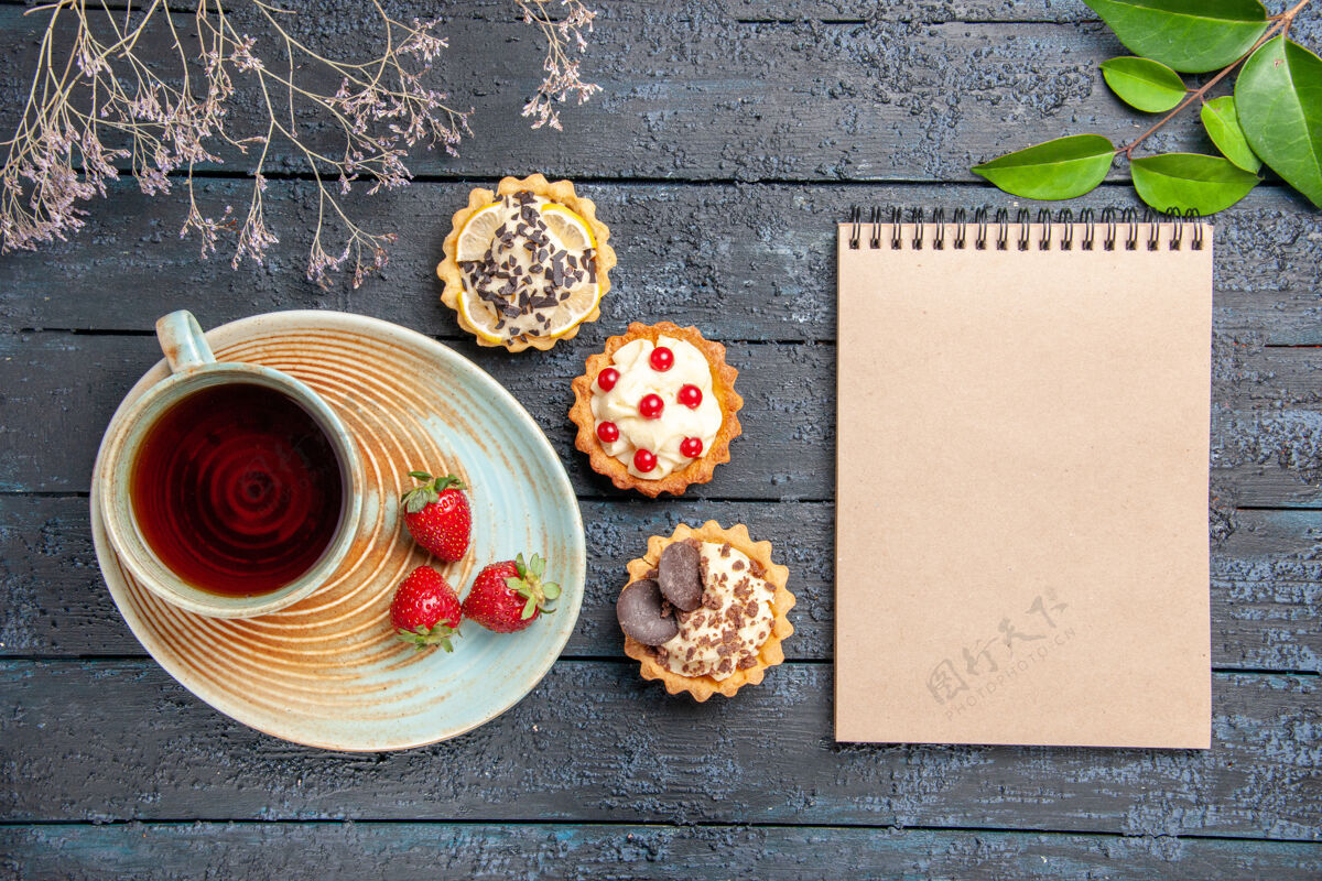 笔记本顶视图茶托馅饼叶上的一杯茶和草莓 深色木桌上的一本笔记本食物茶小吃