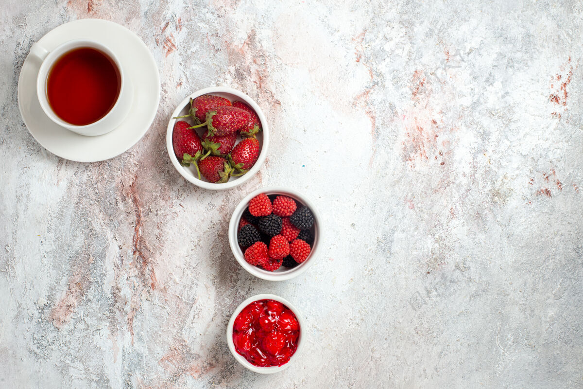 盘子白色表面上有果酱和果酱的茶杯俯视图水果浆果果酱