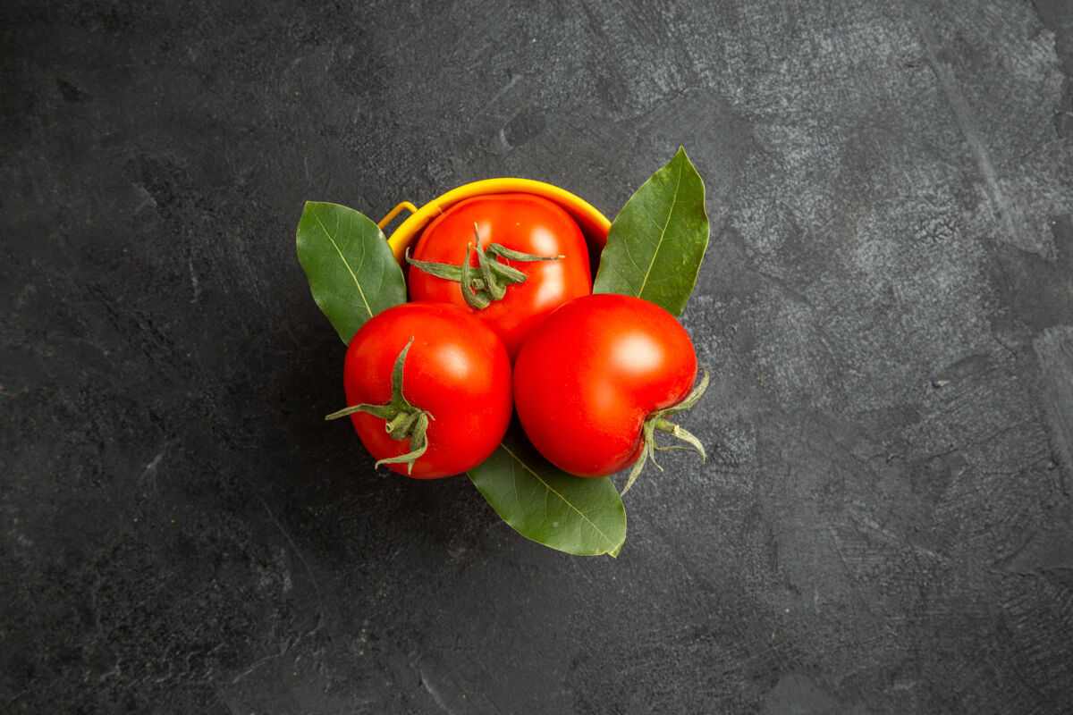 蔬菜顶视图一桶西红柿和月桂叶在黑暗的地面上维管植物番茄深色