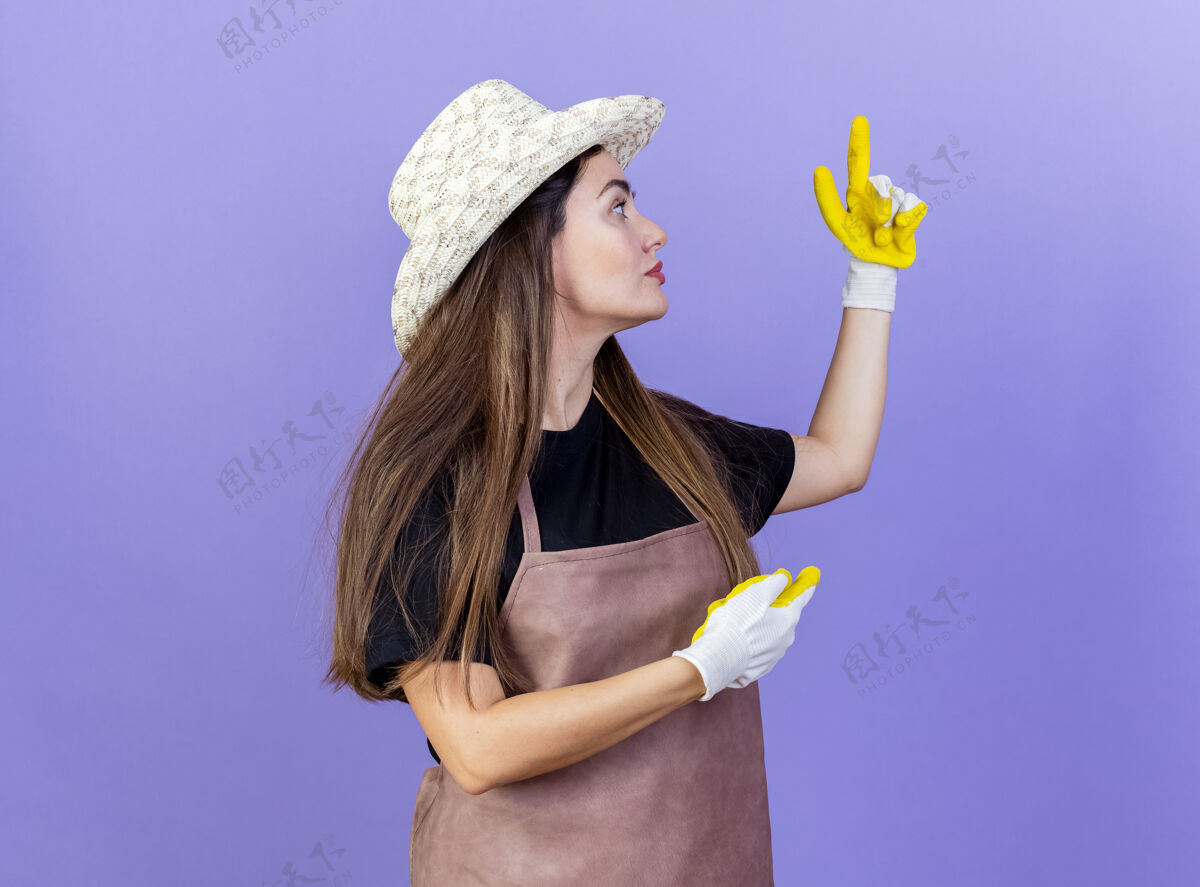 帽子站在侧面看美丽的园丁女孩穿着制服戴着园艺帽和手套点在蓝色的不同侧面隔离点蓝色轮廓