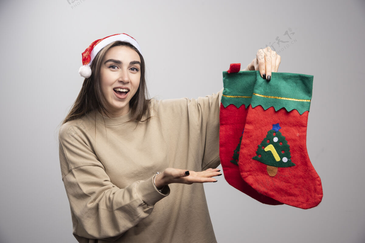 圣诞老人戴着圣诞老人帽子的小女孩在展示两只圣诞袜子惊人节日女性