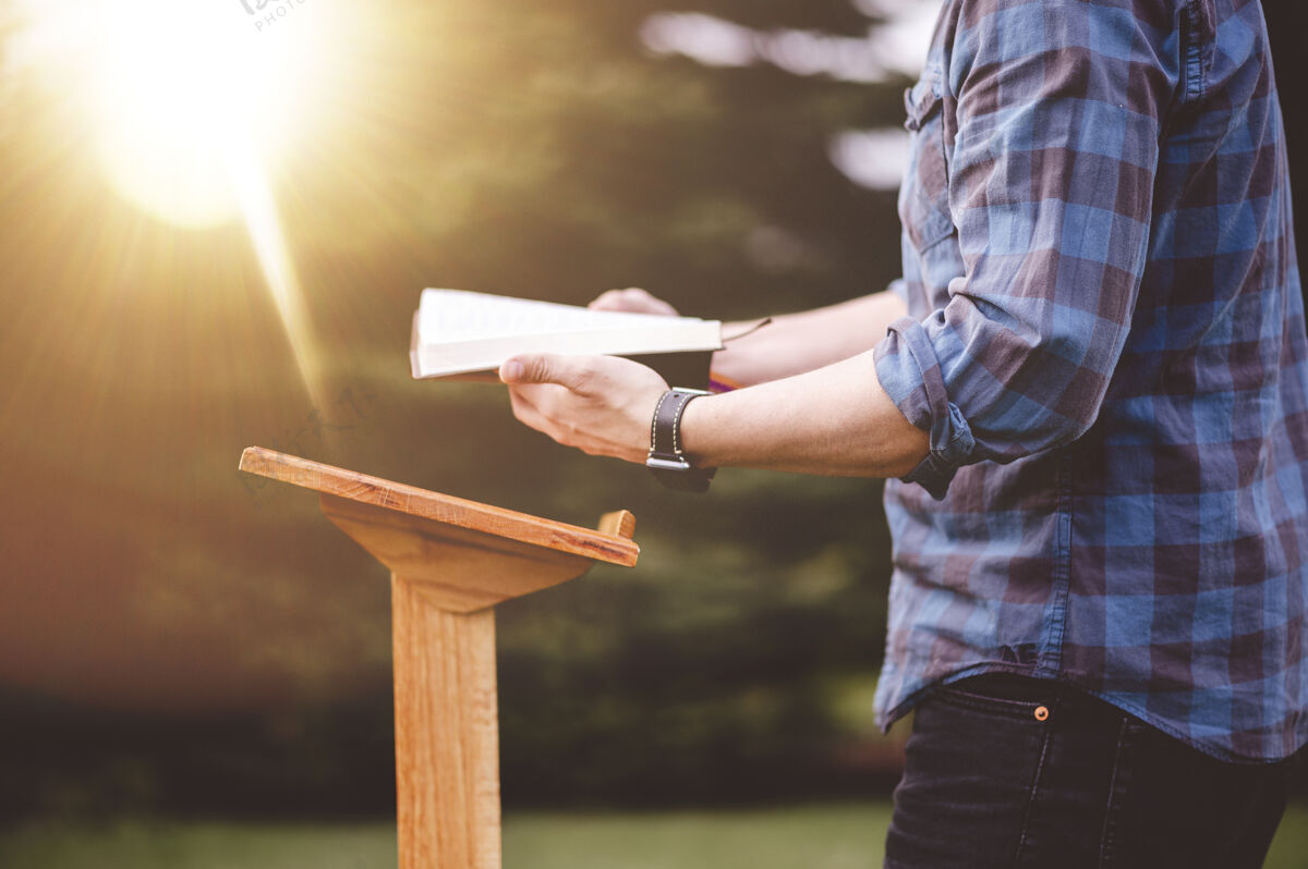 女性一个男人站在讲台旁读圣经的浅焦镜头男性上帝一起
