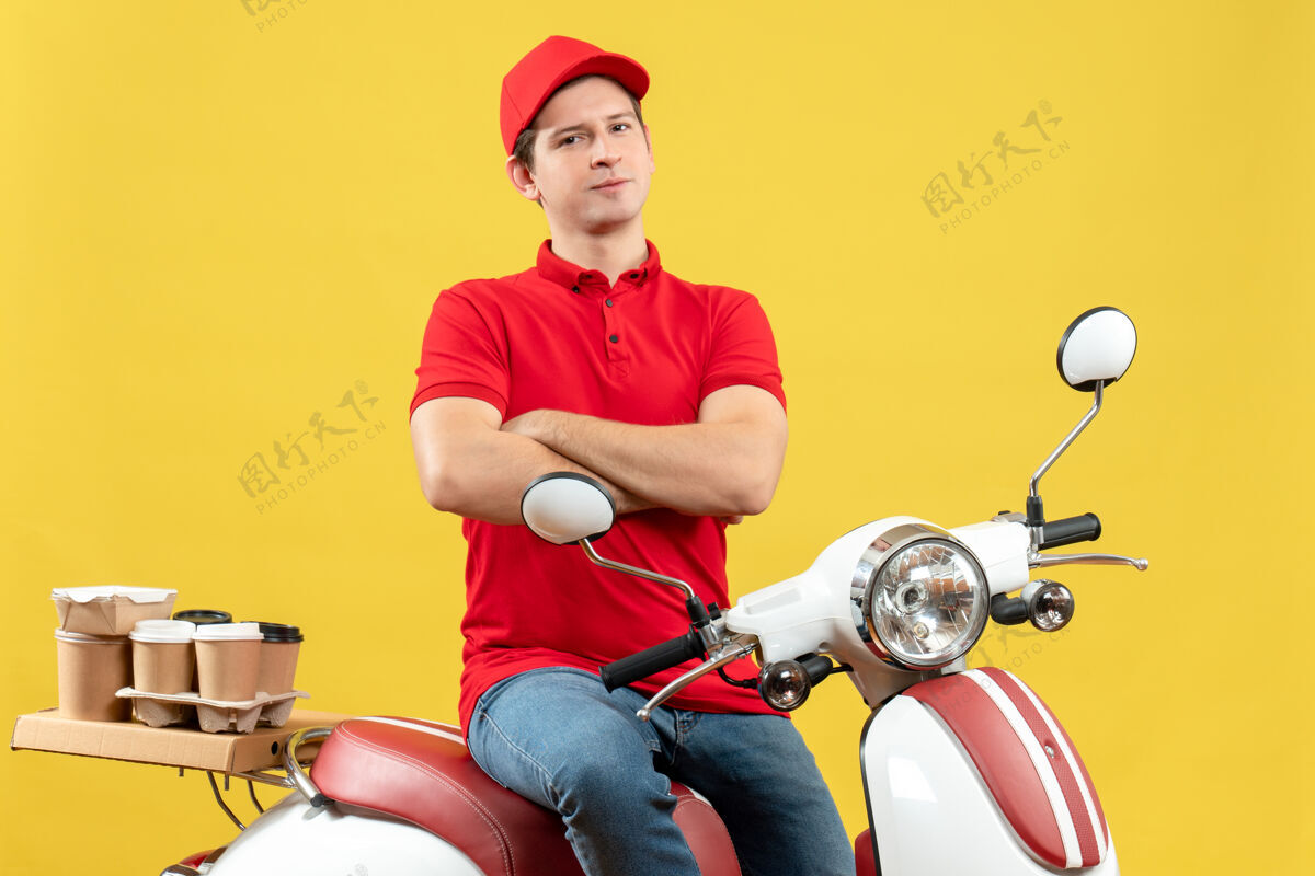 摩托车顶视图自信雄心勃勃的年轻人穿着红色衬衫和帽子 在黄色背景下传递命令交付人命令