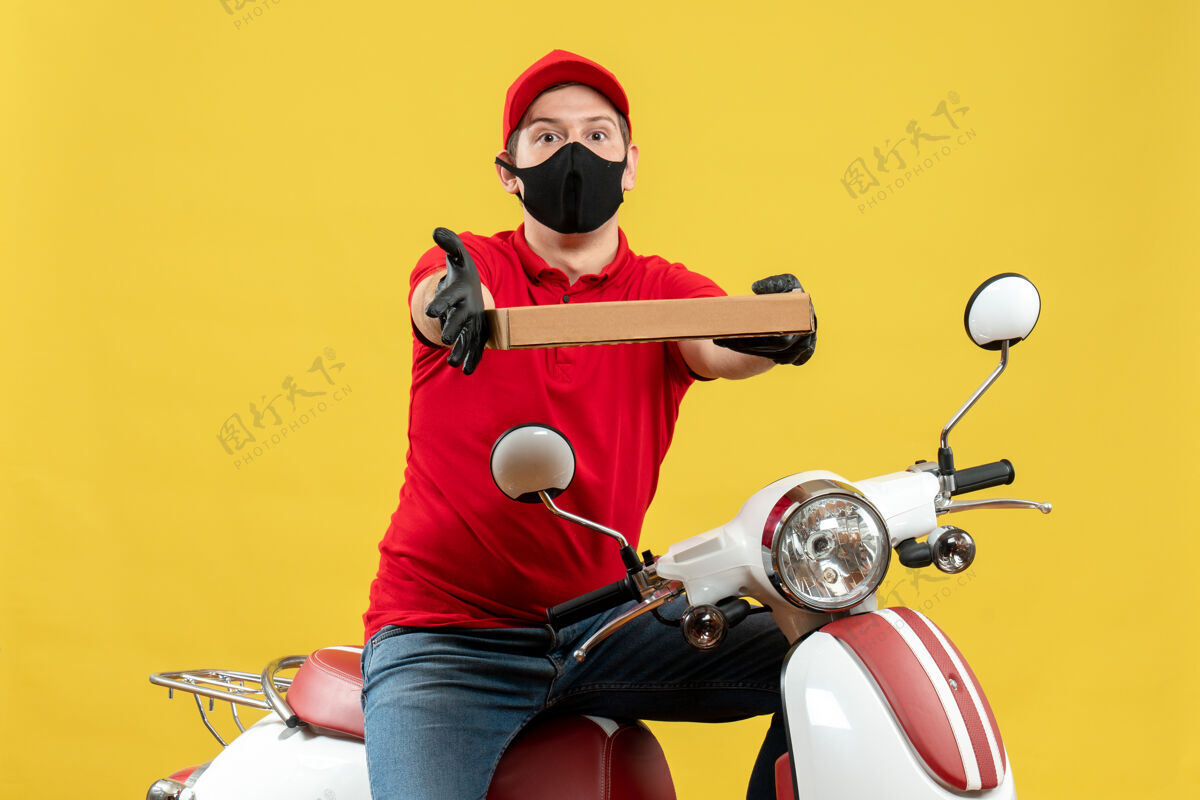人俯视图：身穿红色上衣 戴着帽子手套 戴着医用面罩的快递员坐在滑板车上下命令命令体育给予