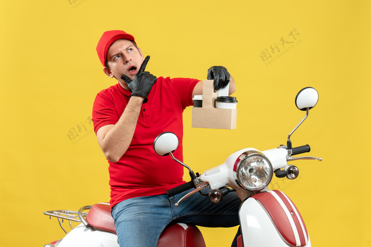 摩托车一个穿着红色上衣 戴着帽子手套 戴着医用面罩的快递员坐在滑板车上拿着订单坐着医疗人