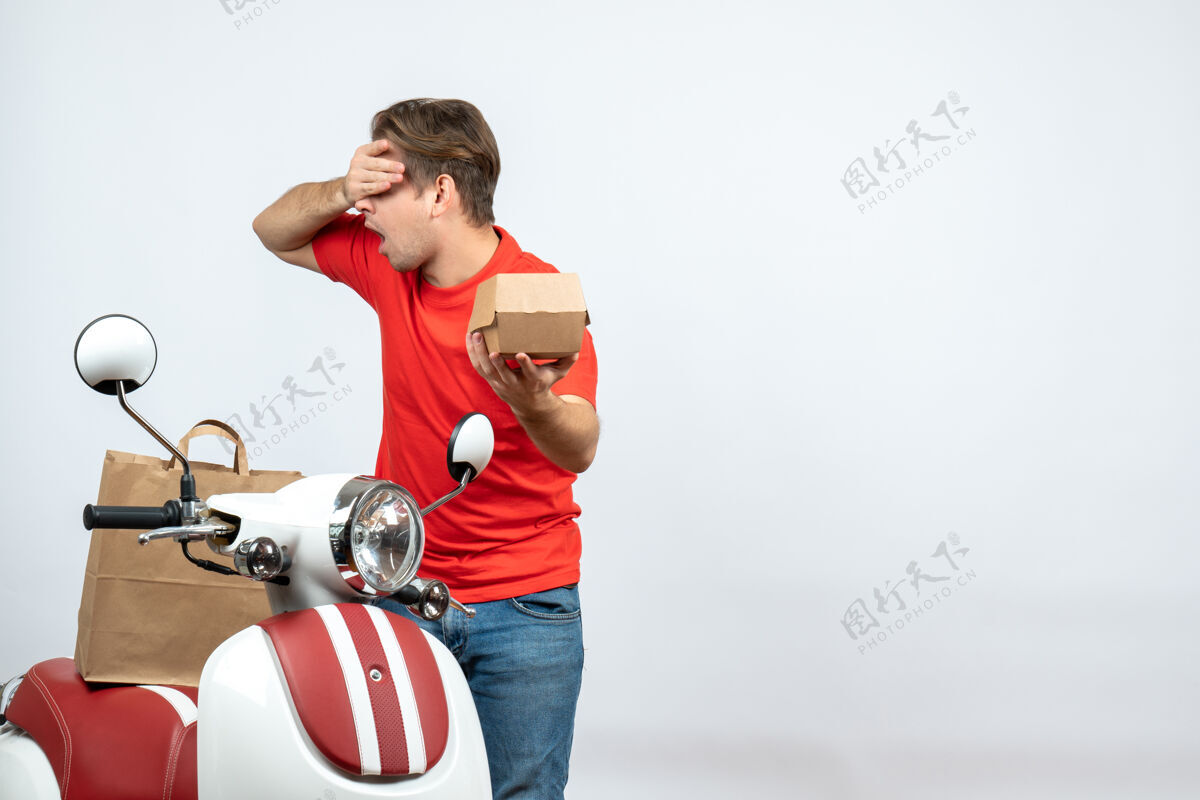 运动顶视图情绪疲惫的送货员穿着红色制服站在滑板车旁 手持白色背景的订单背景红色自行车