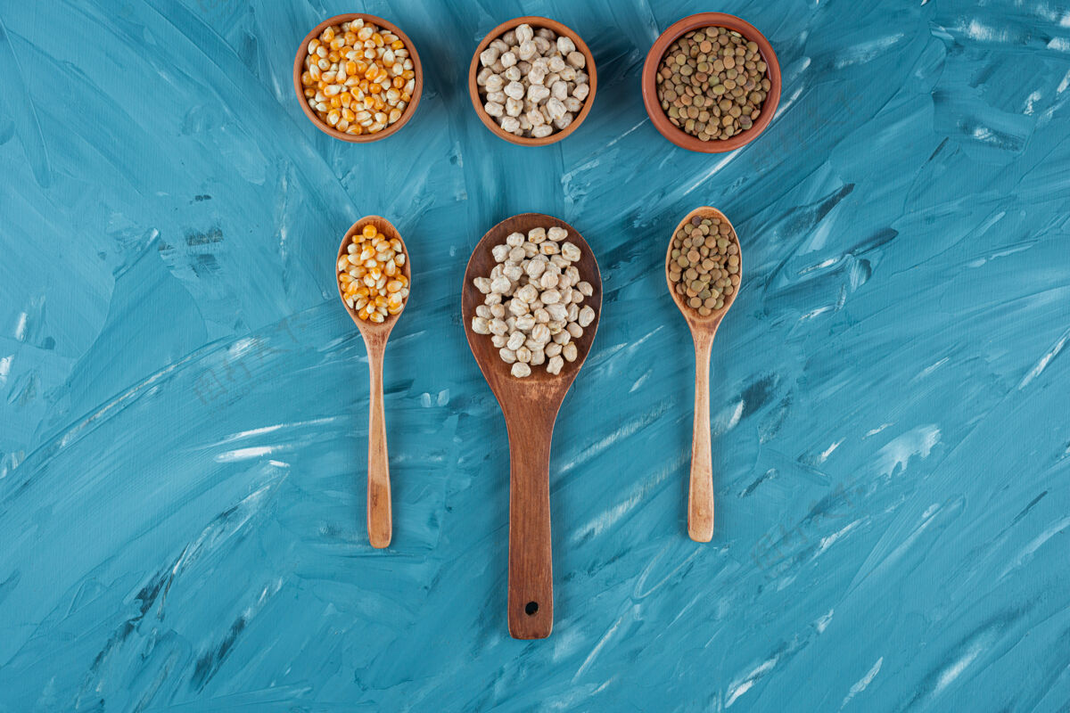 碗三碗生玉米 鹰嘴豆和荞麦放在蓝色的表面上健康什锦营养