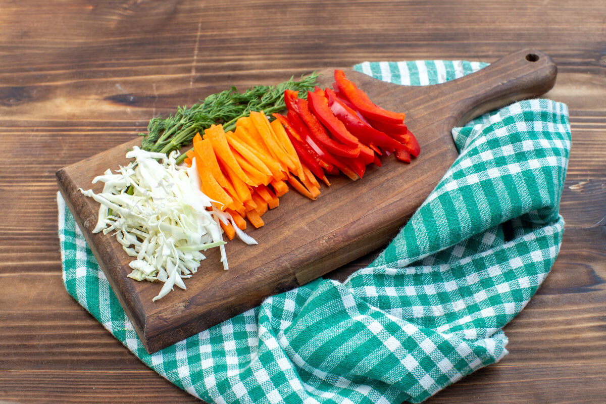 切片蔬菜前视图切菜卷心菜胡萝卜青菜和胡椒切菜板棕色表面沙拉食物绿色