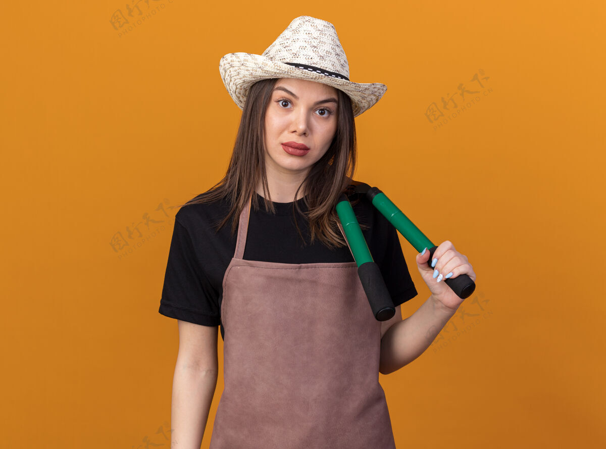 女自信漂亮的白人女园丁戴着园艺帽肩上拿着园艺剪刀放在橘子上剪刀花园自信