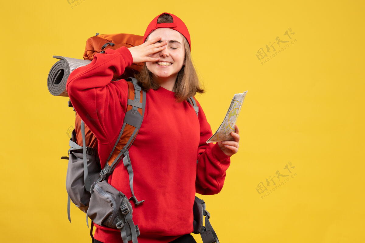 手持前视图快乐的女徒步旅行者红色背包拿着地图把她的手放在眼睛上男性手地图