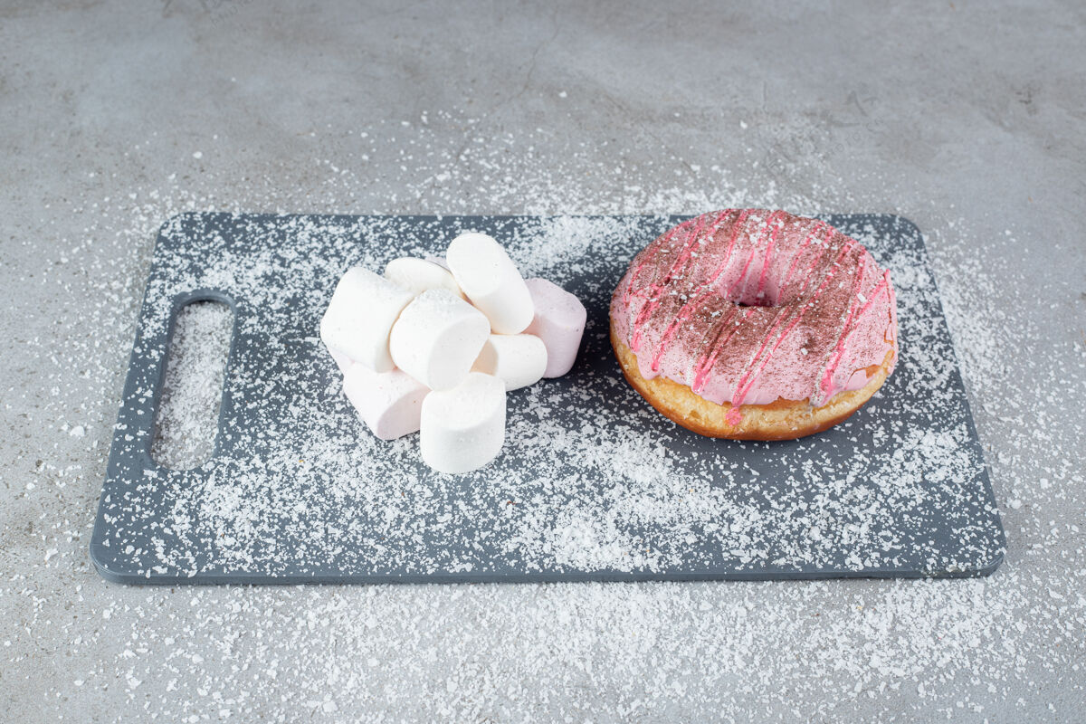 甜点一捆棉花糖和一个甜甜圈放在椰子粉覆盖的大理石板上美味美味美味