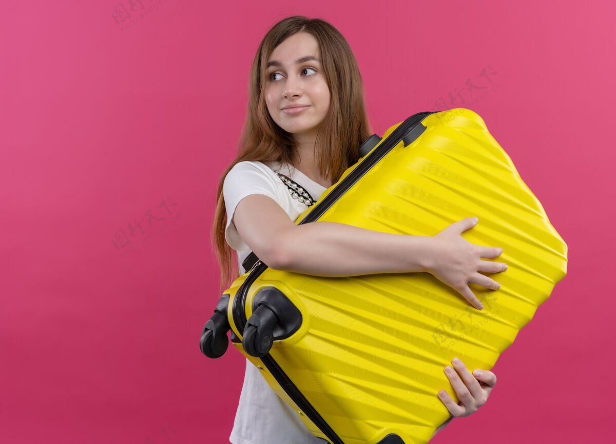 太空高兴的年轻旅行家女孩拿着手提箱 看着左边孤立的粉红色空间和复印空间壁板复制旅行者