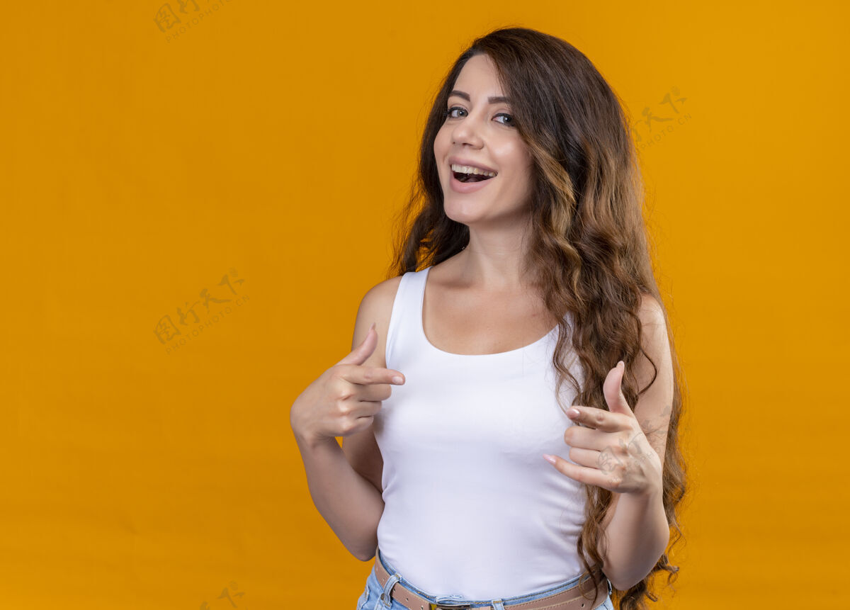 快乐快乐的年轻漂亮的女孩 在孤立的橙色空间里 向上竖起大拇指 用手指着它指向复制向上