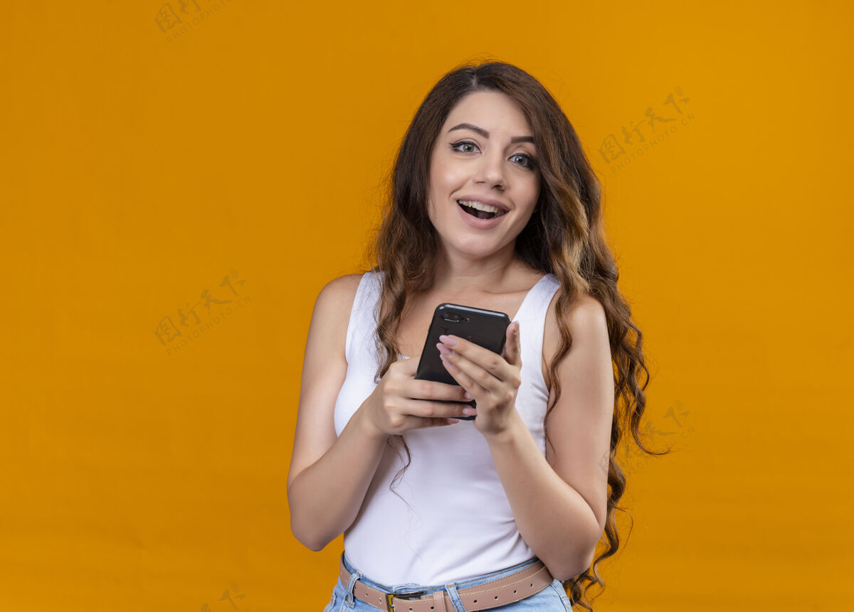 复制快乐的年轻漂亮的女孩拿着手机在孤立的橙色空间和复制空间橙色手机年轻