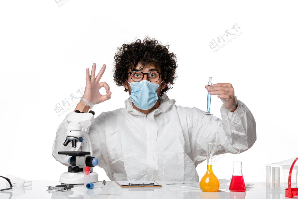 男医生正面图：男医生穿着防护服 戴着口罩 拿着一个装有白色背景病毒的瓶子防护流行病病毒