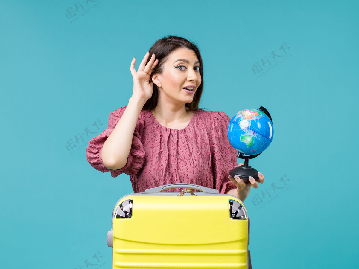 气球前景度假中的女性手持小地球仪在蓝色背景上试听海上旅行的女性度假暑假女人尝试健身