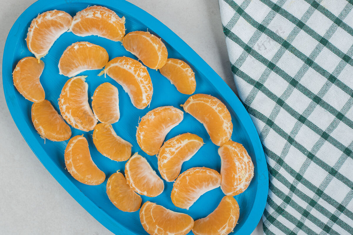 切片蓝色盘子上有多汁的橘子片美味食品多汁
