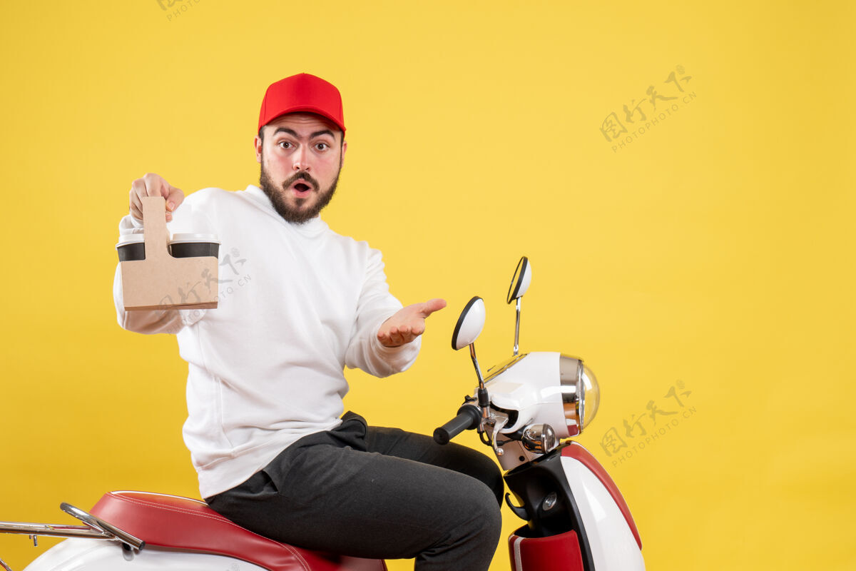 服务黄色墙壁上的男快递员拿着送咖啡的正面图自行车保持男信使