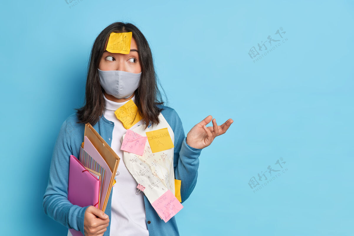 不高兴犹豫不决的亚洲妇女耸耸肩不知道如何使研究工作在冠状病毒大流行期间戴上防护面具工作纸困惑犹豫