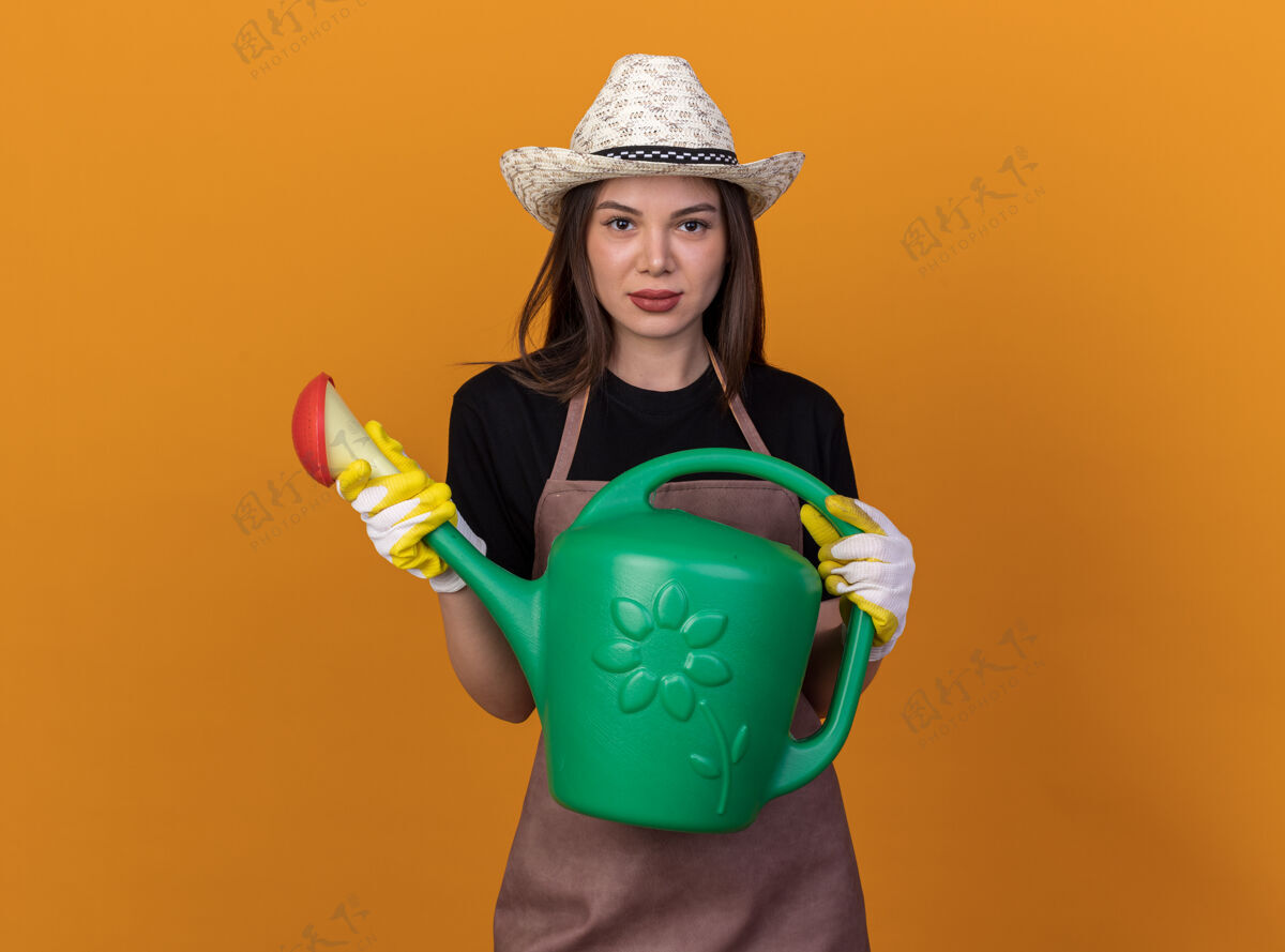 女自信漂亮的白人女园丁戴着园艺帽和手套拿着桔子浇水罐园艺浇水手套