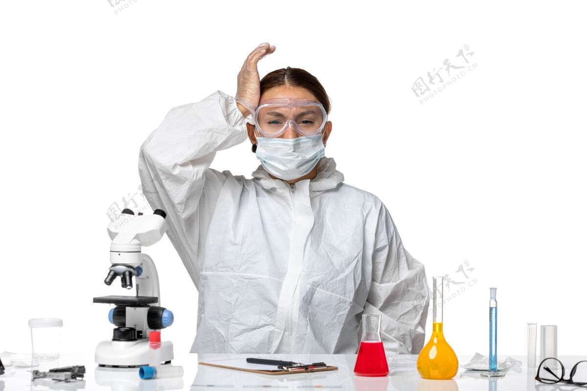 专业前视图：穿着防护服 戴着面罩的女医生坐在白色背景病毒药物covid大流行的解决方案上套装病毒白人