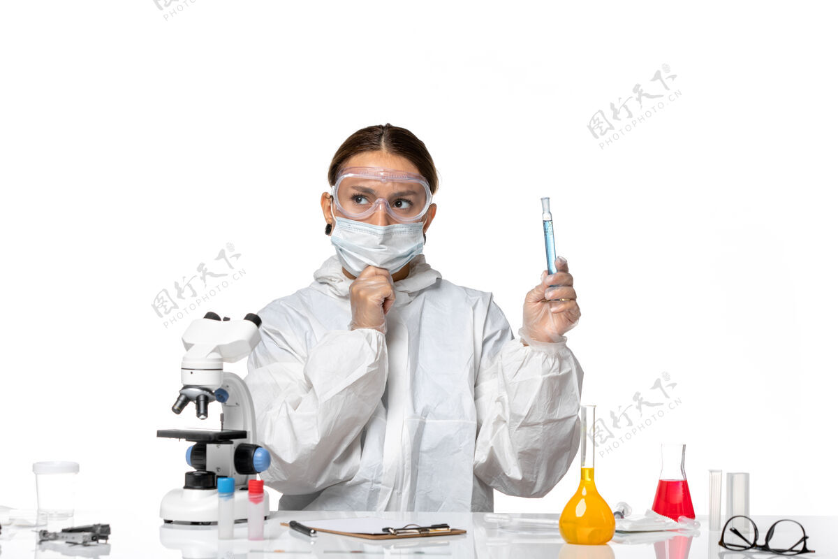 医生前视图：女医生穿着防护服 戴着口罩 拿着装有淡白色背景病毒冠状病毒溶液的烧瓶烧瓶外套思想