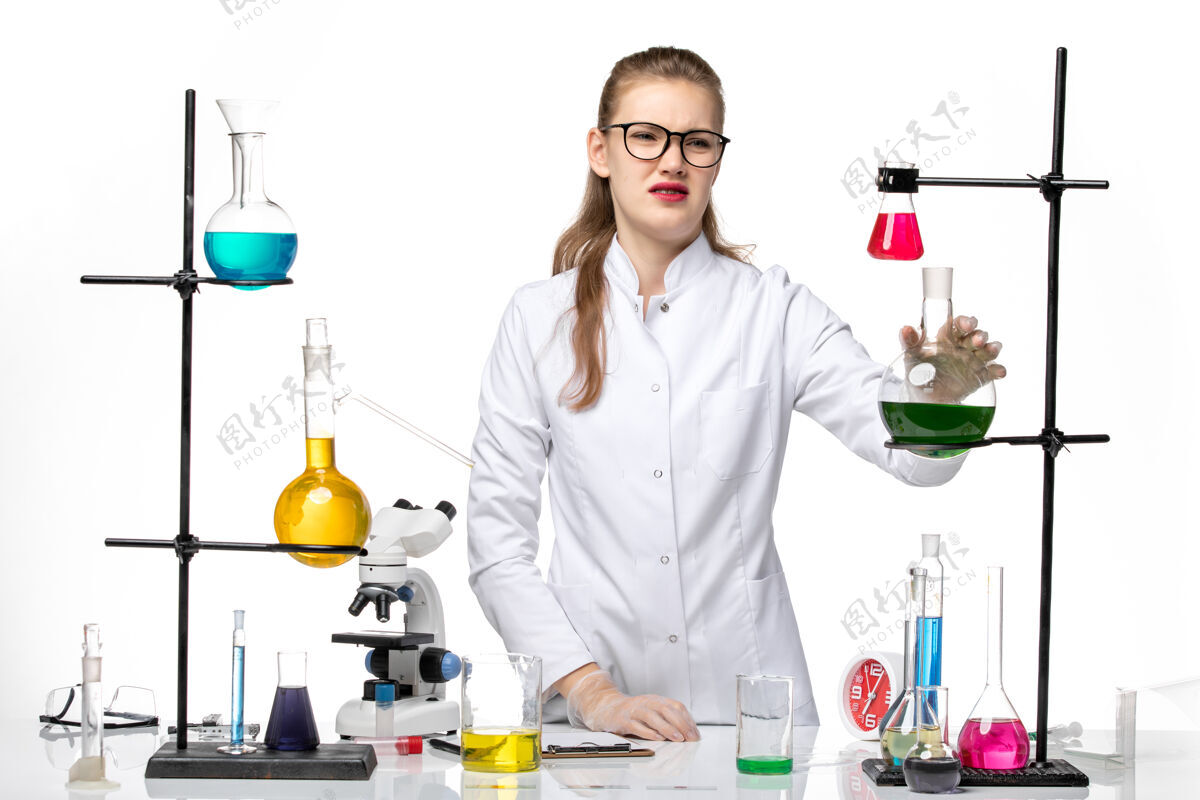 化学前视图穿着医疗服的女化学家拿着白色背景上的绿色溶液烧瓶化学大流行性冠状病毒医学药套装