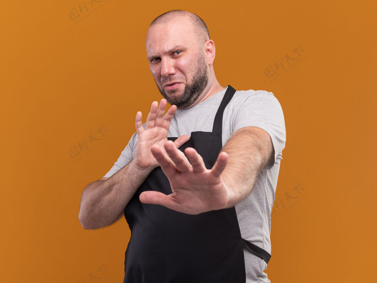 衣服一个穿着制服 神经质的斯拉夫中年男理发师对着隔离在橙色墙上的摄像机伸出双手感觉抱着公民