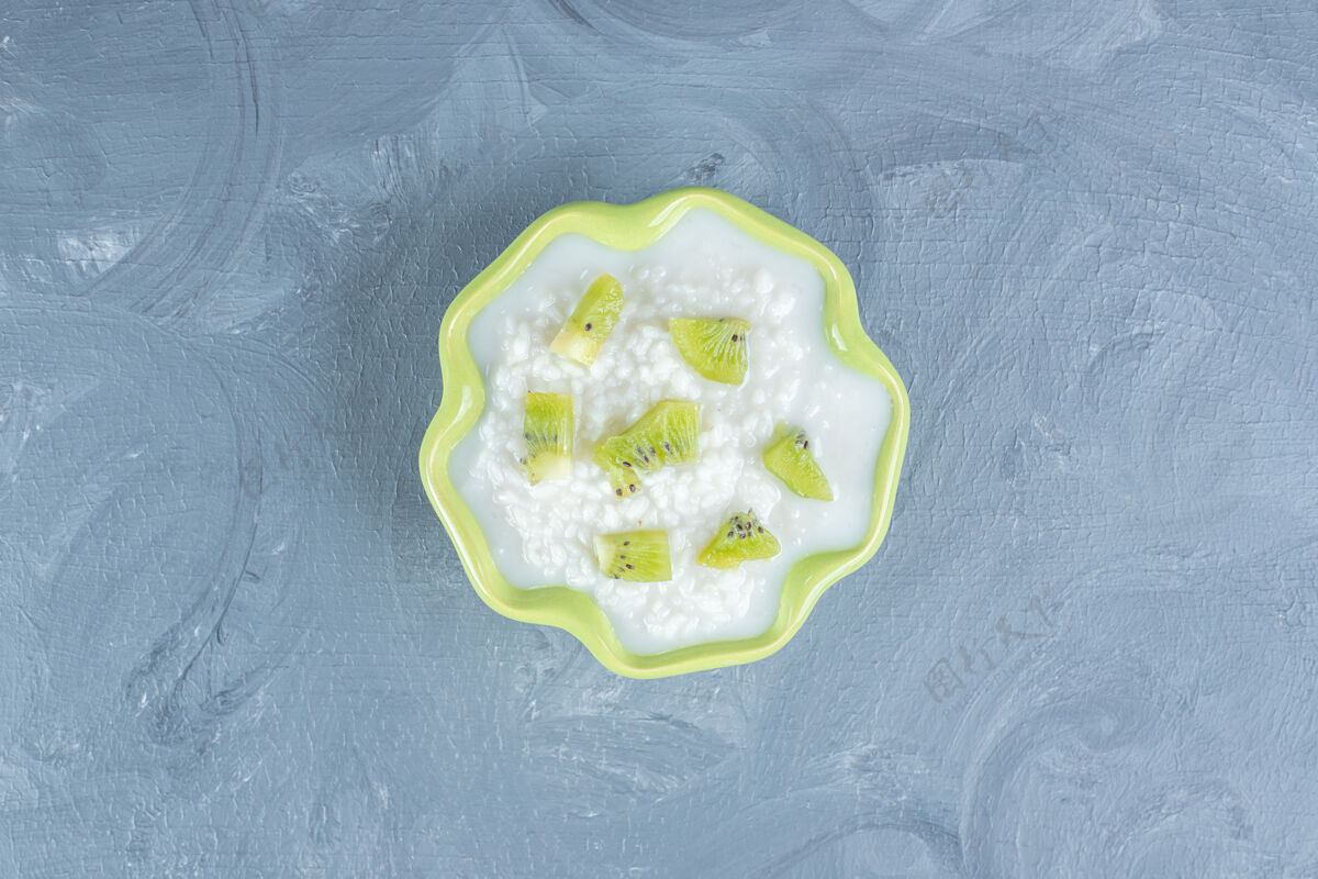 美味绿色的碗里装满了米饭布丁 上面放着奇异果碎片放在大理石桌上猕猴桃碗牛奶