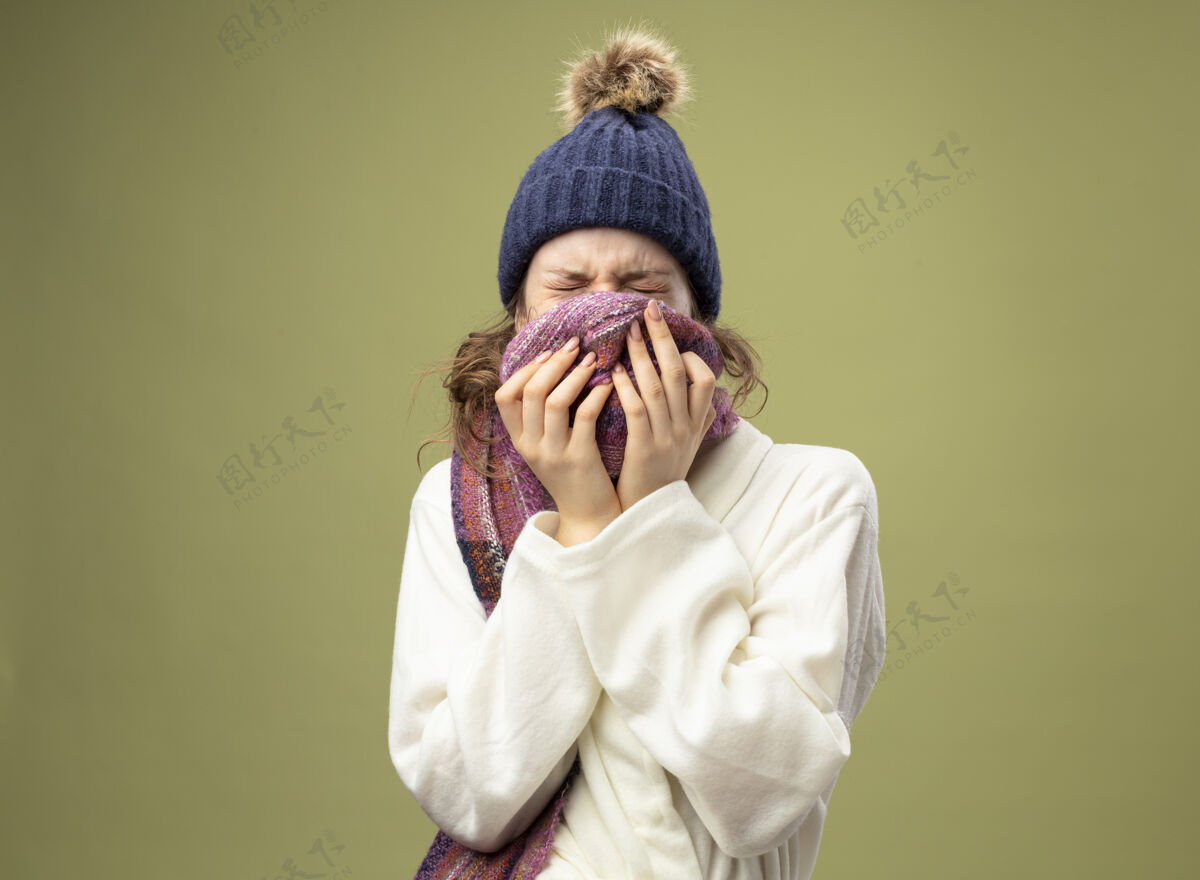 人年轻的病女孩闭着眼睛 穿着白色长袍 戴着带围巾的冬帽 脸上戴着围巾帽子覆盖长袍