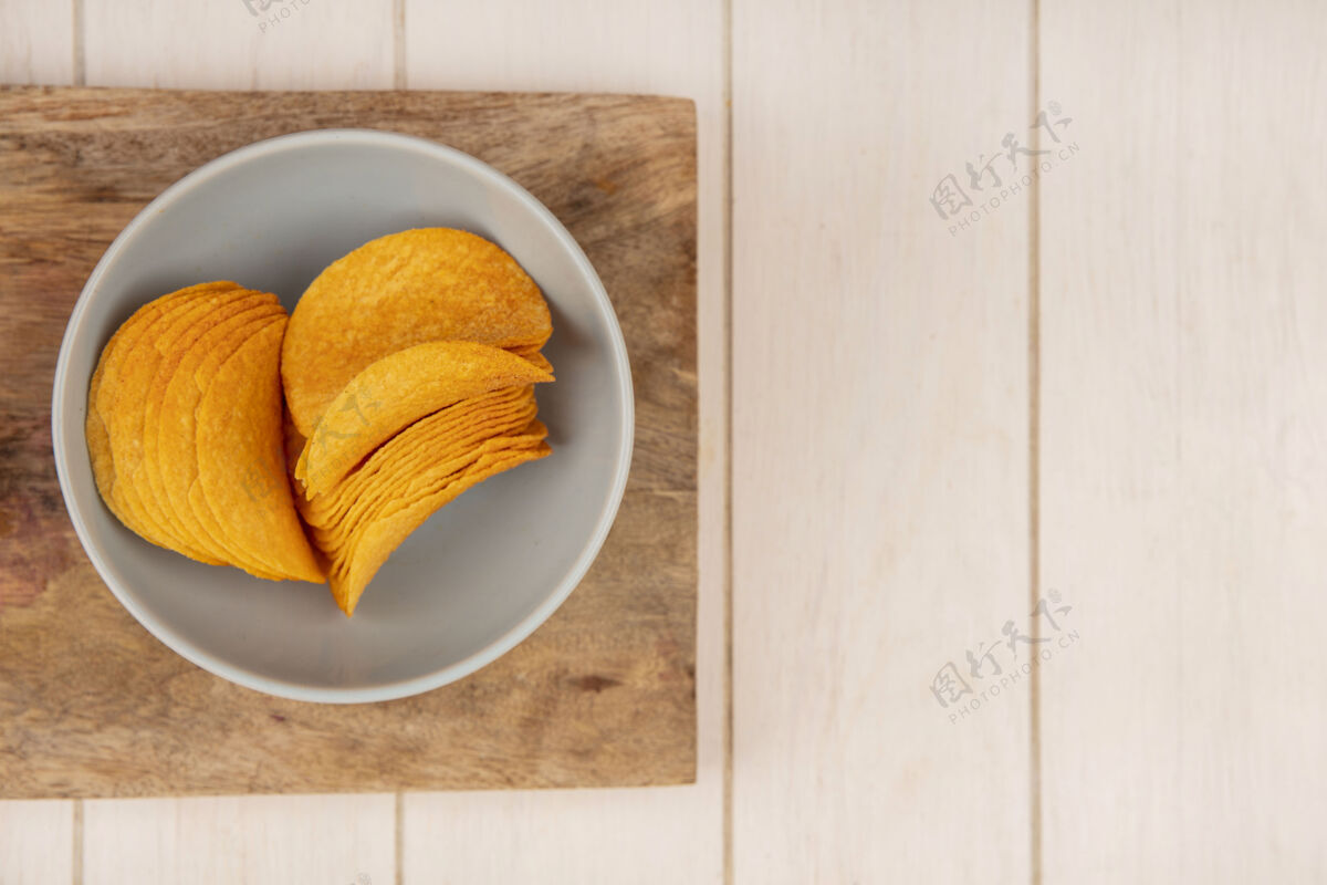 薯条米色木制桌子上的木制厨房板上的碗上美味脆薯片的俯视图 带有复印空间木板厨房小吃