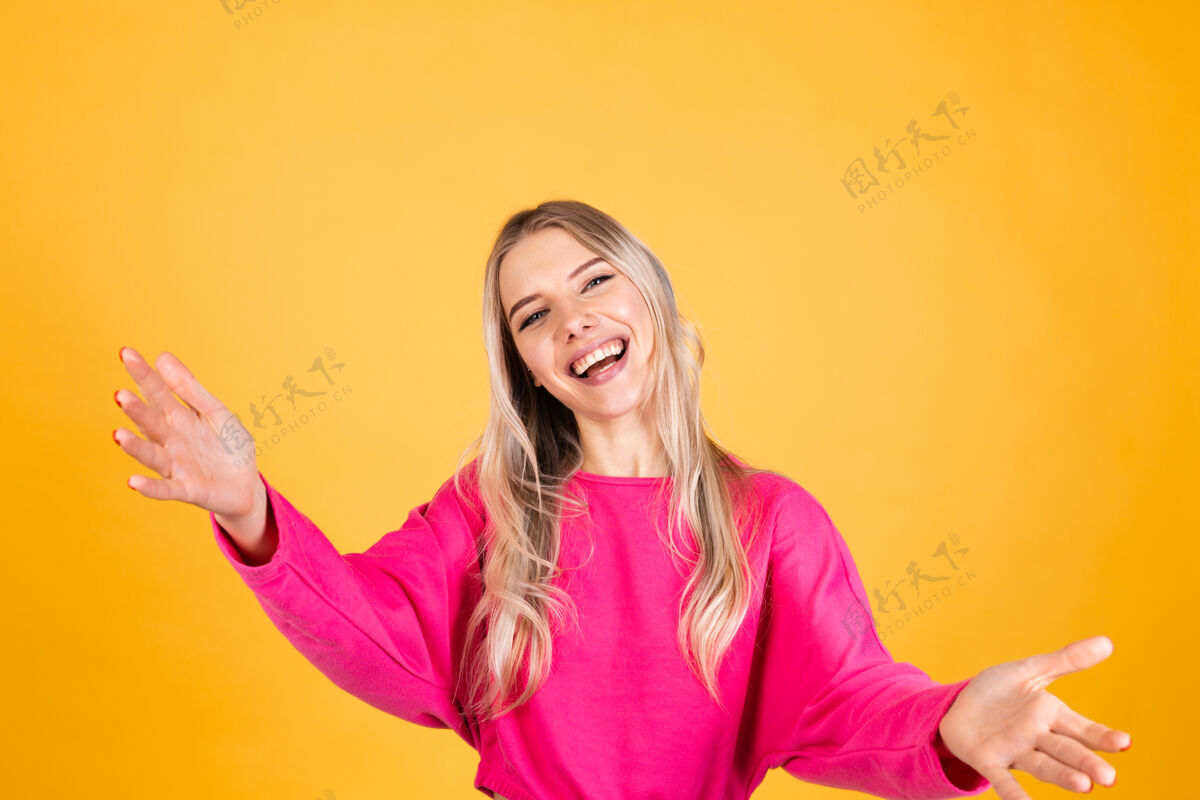 手臂黄色墙上穿粉红色上衣的漂亮欧洲女人欢乐爱来