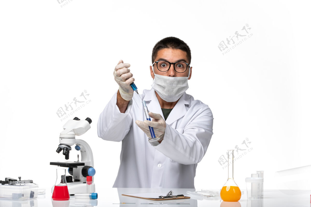 实验室外套正面图：由于科维德在白色办公桌上工作 男医生穿着白色医疗服 带着面罩男性医疗办公桌